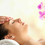 Close up  portrait of young Female Facial massage in spa. Therapist massaging woman’s head against bright colorful background.