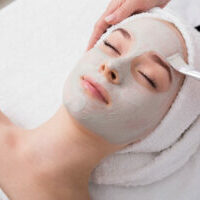 Face peeling mask, spa beauty treatment, skincare. Woman getting facial care by beautician at spa salon, side view, close-up